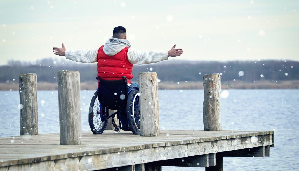 Schwere Krankheiten Vorsorge: ein junger Mann im Rollstuhl kann trotzdem sein Leben genießen!